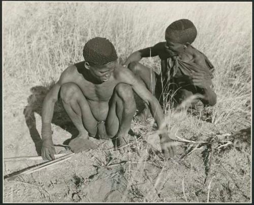 ≠Gao (headman of Band 3) and "/Qui Hunter" (≠Gao's sister's husband) starting to make fire, showing pile of sticks ready for the fire (print is a cropped image)