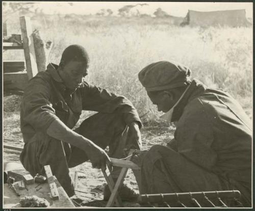 Heinrich Neumann and an unidentified man repairing a stool (print is a cropped image)