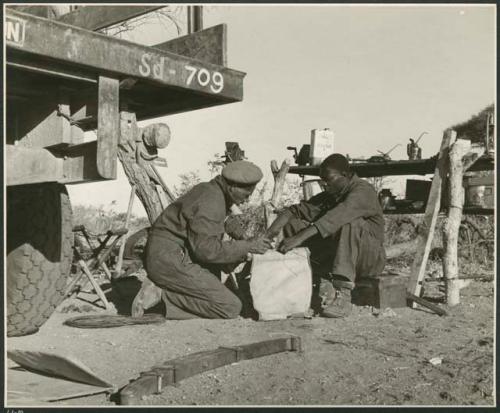 Heinrich Neumann and an unidentified man fixing a stool (print is a cropped image)