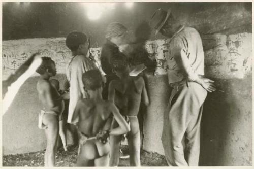 Elizabeth Marshall Thomas (taking notes) with children, inside hut