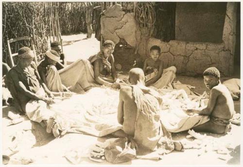 People husking corn in Okwa house courtyard (print is a cropped image)