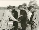 Group of men receiving food from Lorna Marshall (print is a cropped image)