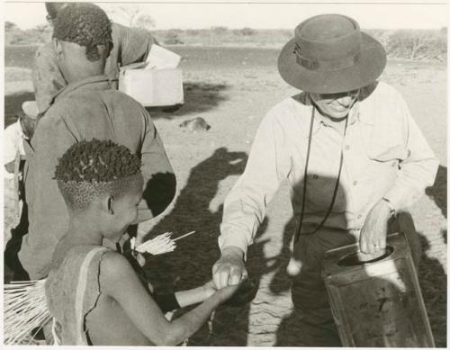 Group of men receiving food from Lorna Marshall (print is a cropped image)