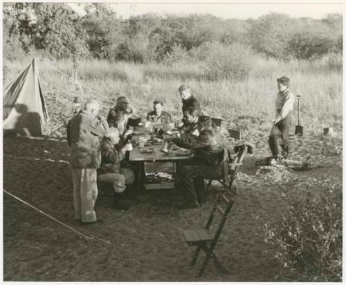 Knoble and his group sitting at a table eating (print is a cropped image)