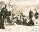 Group of people sitting under a tree (print is a cropped image)