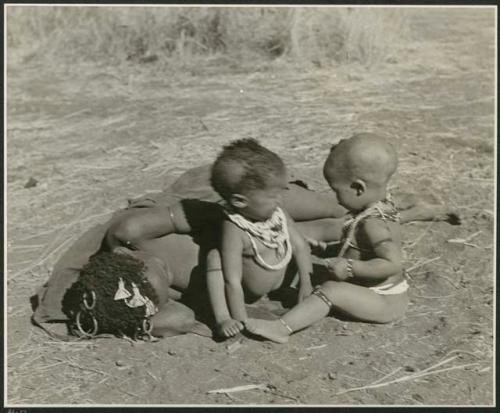 !Ungka, ≠Toma's sister, lying down, with her baby Sa≠gai and Norna sitting next to her (print is a cropped image)