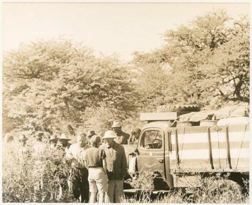 Elizabeth Marshall Thomas and Laurence Marshall talking by the truck with group of people behind them (print is a cropped image)