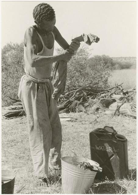 /Gishay washing his clothes using a bucket filled with water (print is a cropped image)