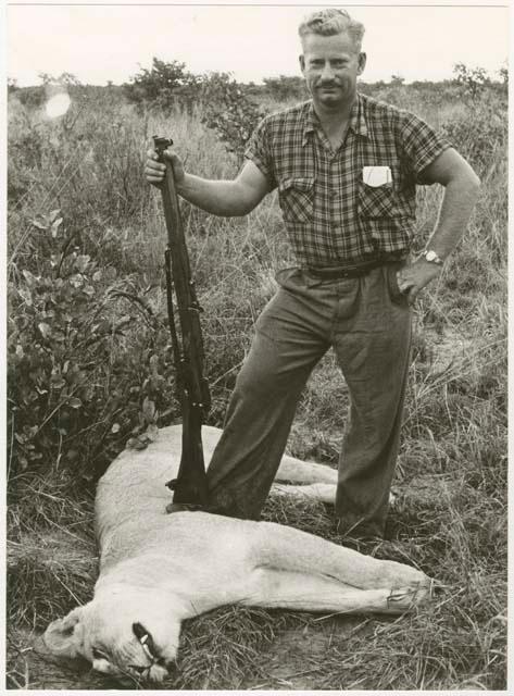 Theunis Berger standing with a gun over a dead lion (print is a cropped image)