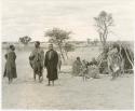 Group sitting in front of a grass hut at Kungwane (print is a cropped image)