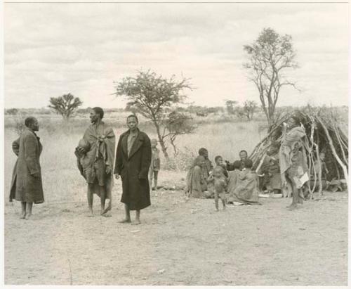 Group sitting in front of a grass hut at Kungwane (print is a cropped image)