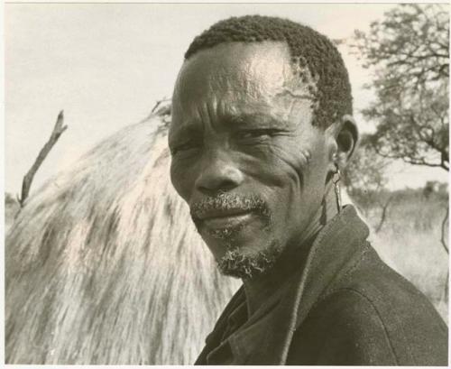 Man wearing a coat looking forward (print is a cropped image)