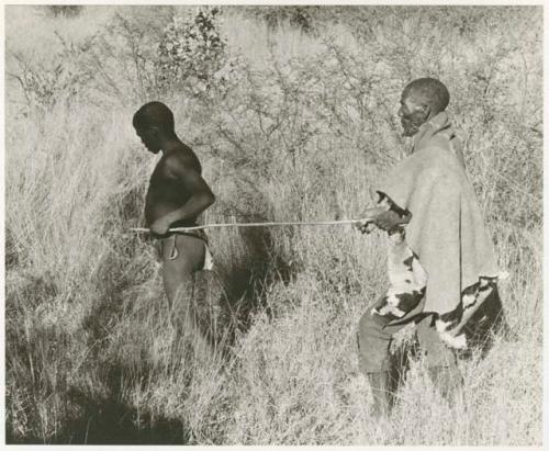 Elderly blind man led by a boy using a long stick (print is a cropped image)