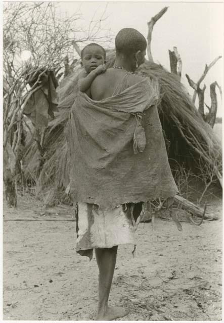 Woman carrying her child, view from the back (print is a cropped image)