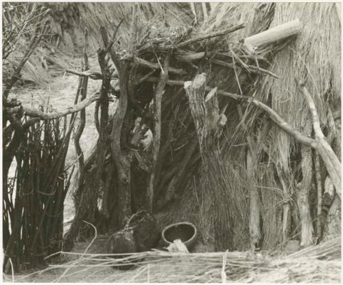 Outside of a skerm showing wooden pole structure (print is a cropped image)