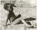 Child reclining on the ground (print is a cropped image)