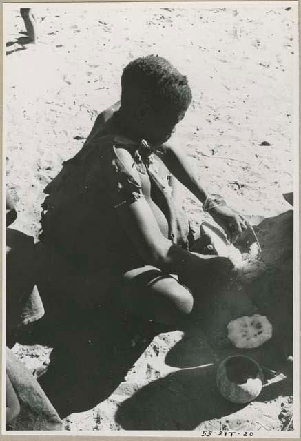 Woman seated scraping a tsama melon