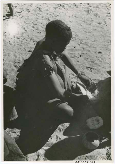 Woman seated scraping a tsama melon