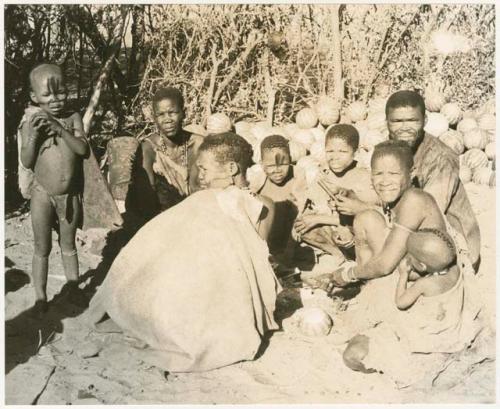 Group sitting by a pile of tsama melons (print is a cropped image)