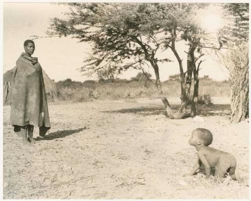 Child crawling, Mogatsiposi standing in the background wearing a kaross (print is a cropped image)