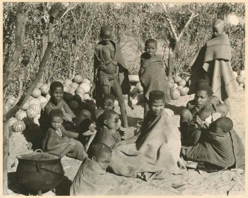 Group sitting by a pile of tsama melons (print is a cropped image)