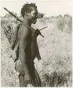 Man carrying a stick on his shoulder and on his back (print is a cropped image)