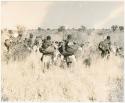 Women walking, part of a group moving to a new encampment (print is a cropped image)