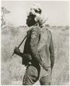 Man with a fur cap and two large horns on his back (print is a cropped image)