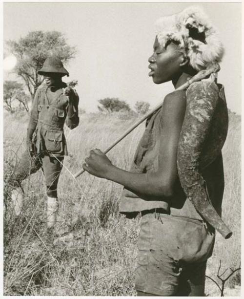 Headman wearing a hat, standing near a boy wearing a fur cap (print is a cropped image)