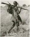 Man carrying animal traps and a gun (print is a cropped image)