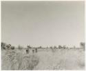 Group of people walking, moving to a new encampment (print is a cropped image)