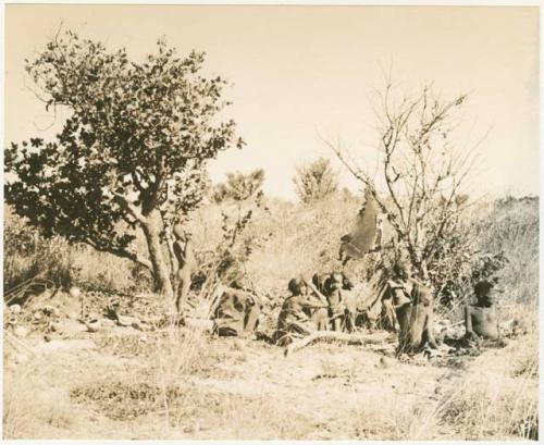 Group of people sitting by a fire, distant view (print is a cropped image)