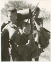 Tsekue carrying a mortar and N!whakwe, DaSi!na standing behind (print is a cropped image)