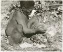 Oukwane taking a handful of gemsbok stomach contents (print is a cropped image)