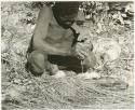 Oukwane squeezing gemsbok stomach contents using grass as a sieve (print is a cropped image)