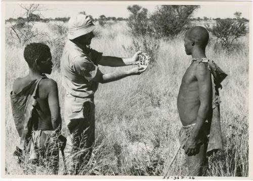 Robert Story holding a Polaroid picture for Oukwane and !Gai to see