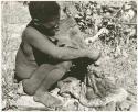 Oukwane holding the gemsbok stomach bag partly filled (print is a cropped image)