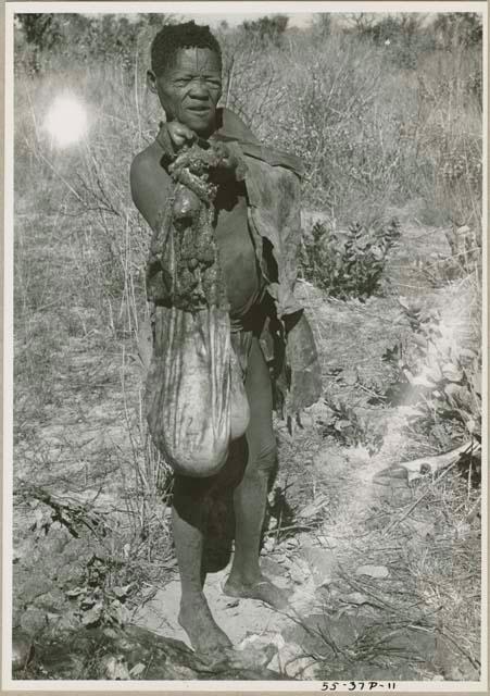 Oukwane standing, holding the gemsbok stomach bag (print is a cropped image)