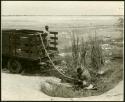 Man pumping water from a waterhole at Gautscha into water barrels on a truck and another man standing in the bed of the truck