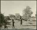 Woman carrying wood into a werft and a child in the foreground