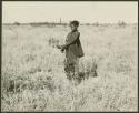 Girl standing in a tsĩ field, side view