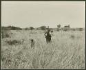 Woman looking for tsĩ and a child standing nearby, distant view