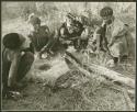 Husband, wife, her younger sister, and a boy sitting around a fire, roasting tsĩ