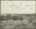 Power Wagon at a waterhole and Gautscha Pan in the background; three people filling barrels with buckets of water