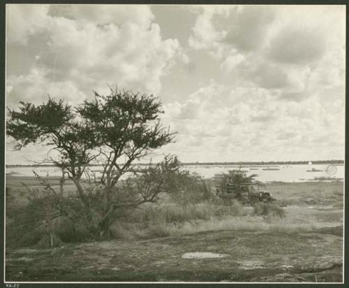 Power Wagon at a waterhole and Gautscha Pan in the background; three people filling barrels with buckets of water