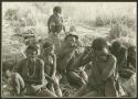 Ju/'hoan men and women sitting and a child crouching on a rock