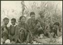 Ju/'hoan women and children sitting; man standing in the background