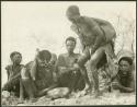 Group of Ju/'hoansi sitting; one woman is half crouching