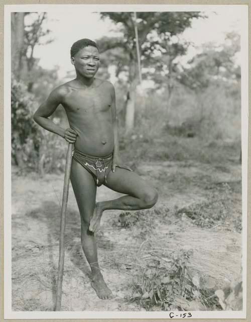 Man standing on one leg leaning against his stick