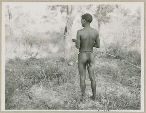 Man holding a spring-hare prodder, seen from behind